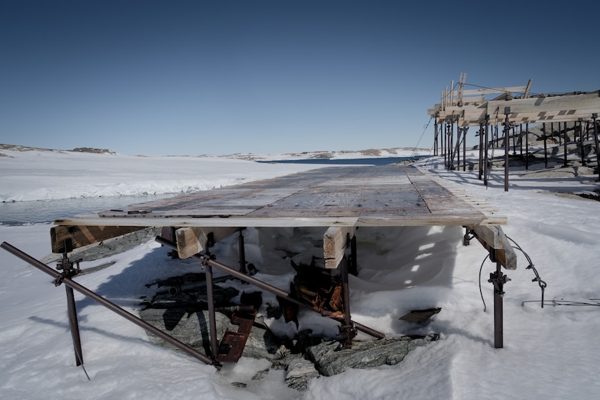 Dilapidated ram and building in icy environment.