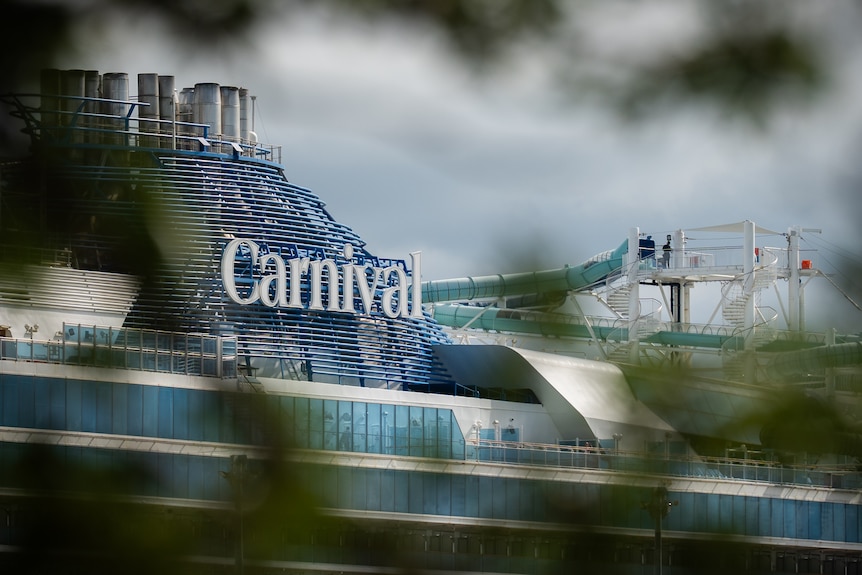 The upper levels of a large cruise ship docked in a harbour. 
