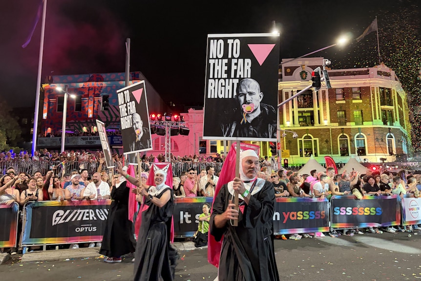 Men dressed as nuns hold signs with the image of Thomas Sewell