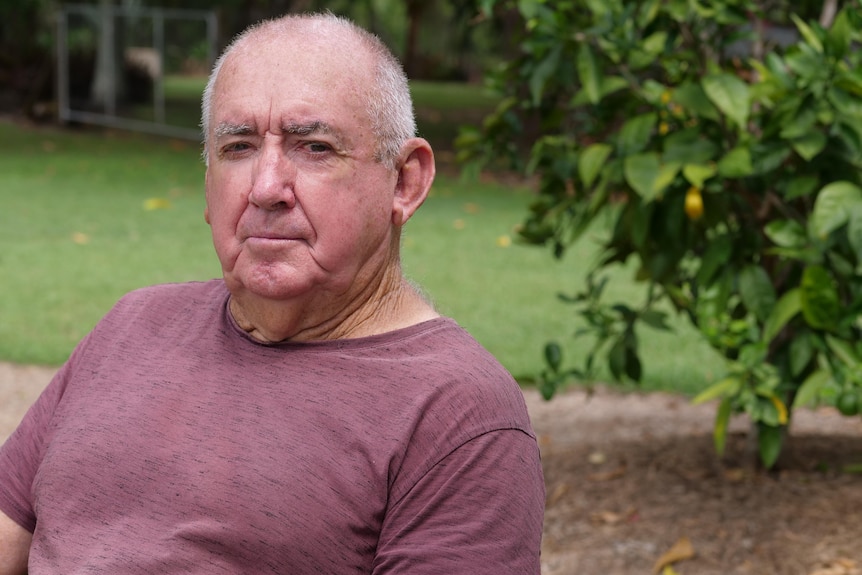 A man looking concerned, he is wearing a dull red brown shirt