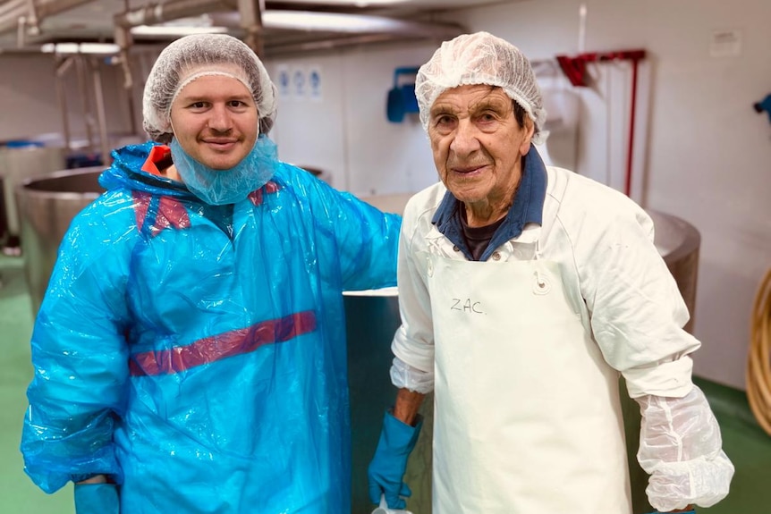 Two men in protective clothing working on a dairy floor.