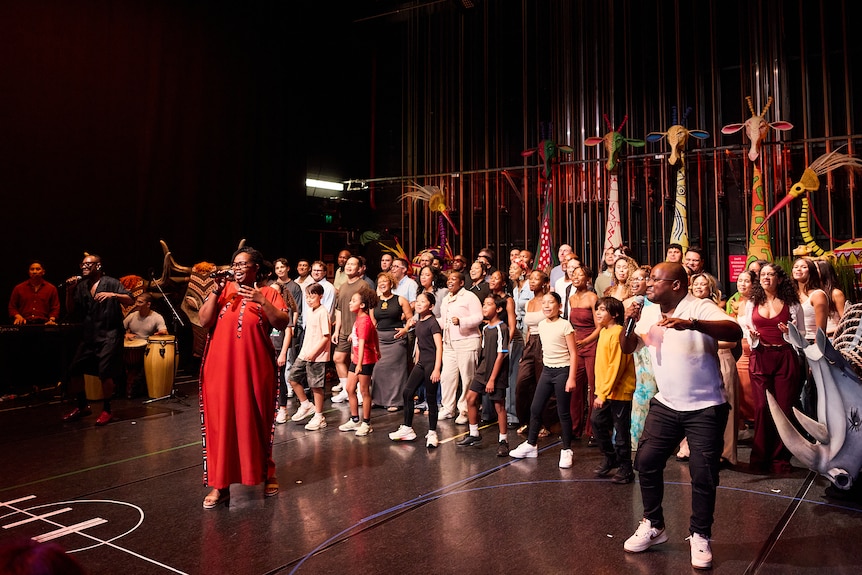 A crowd of people singing and dancing at rehearsals.