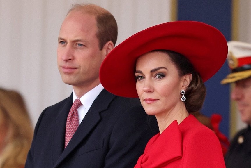 Prince William and Princess Catherine attend a ceremony. Catherine is wearing a large red hat.