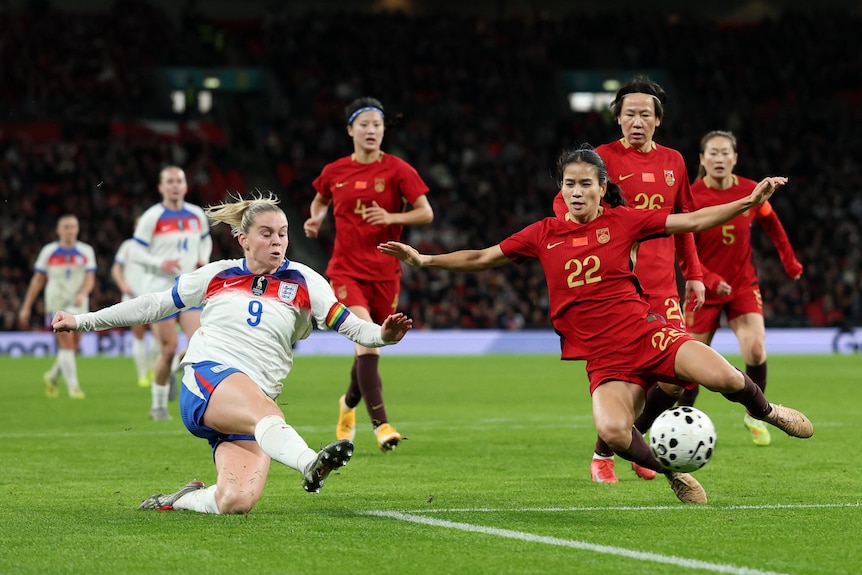 Woman soccer player kicks ball as opponent tried to tackle