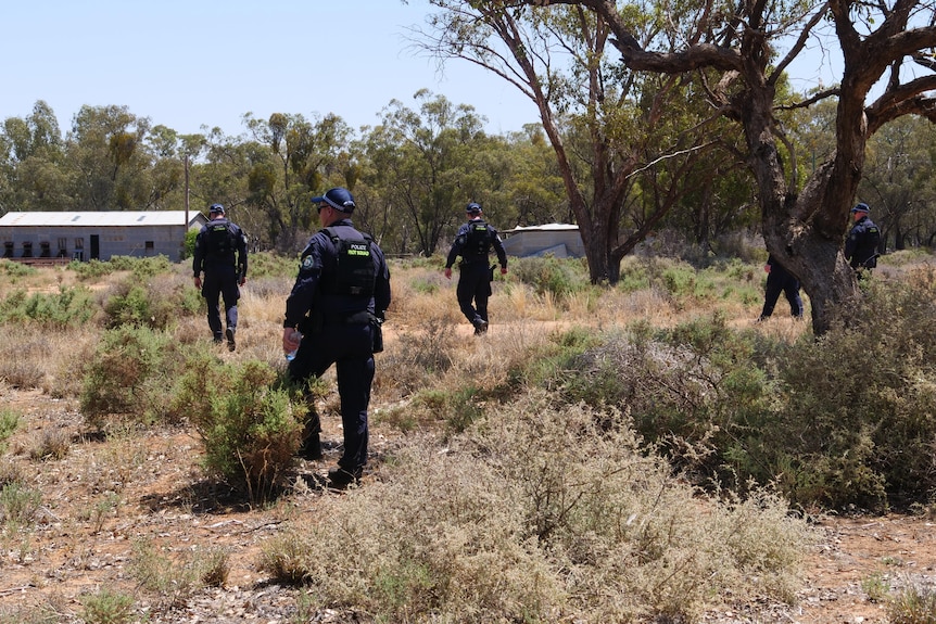 riot squad police walk through scrub property line search