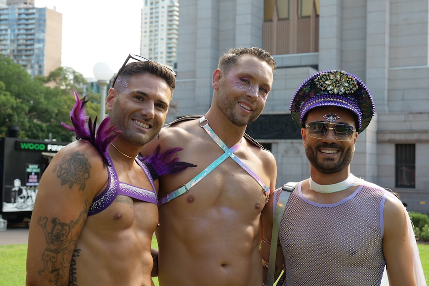 Three shirtless men pose for a photo.