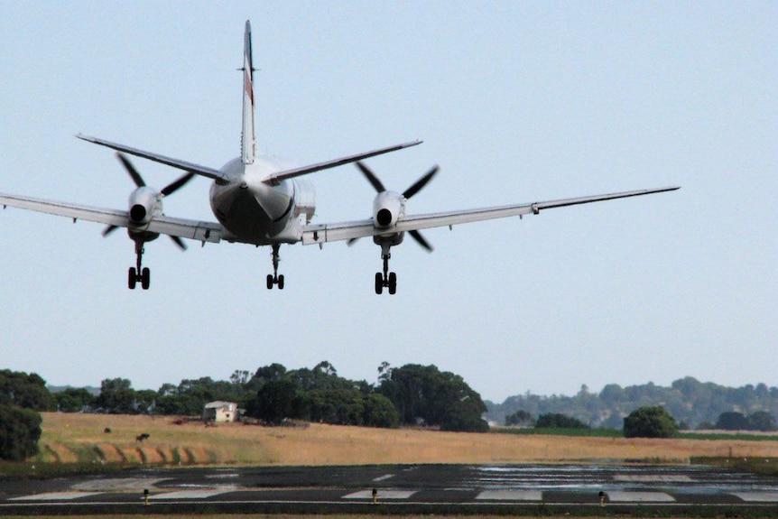 Photo of a plane several metres in the sky, taking off at a regional airport