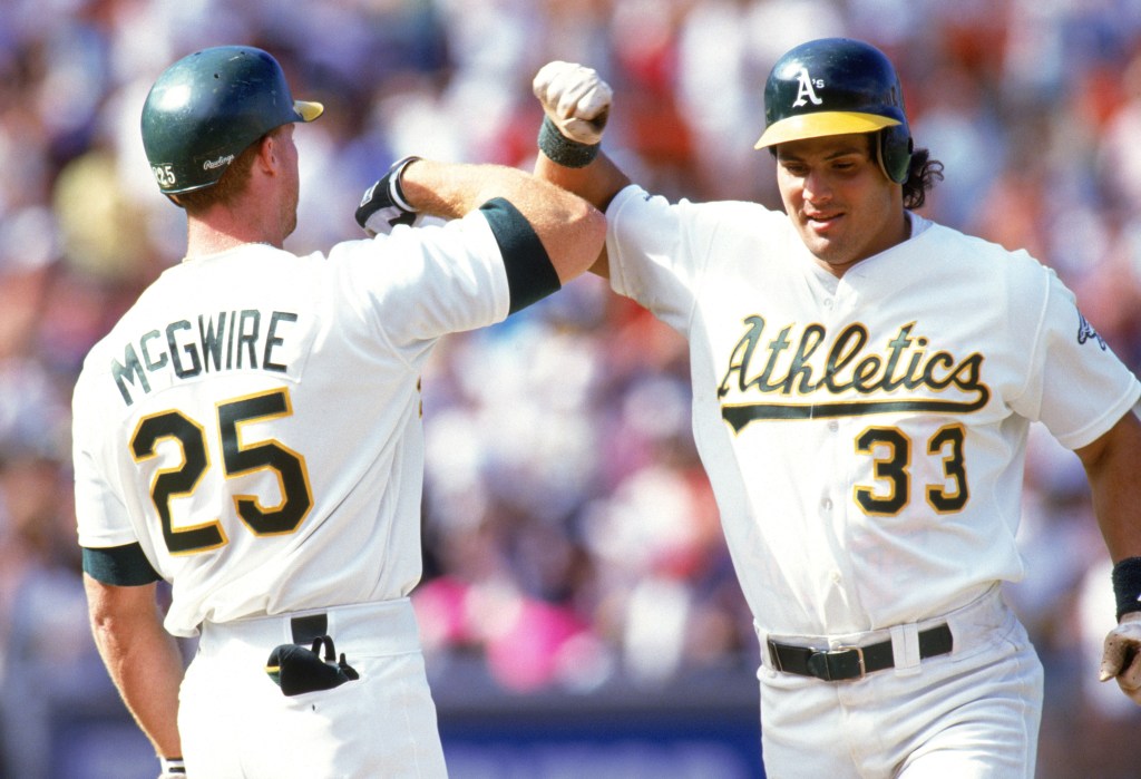 Jose Canseco high-fives fellow Oakland Athletics player Mark McGwire.