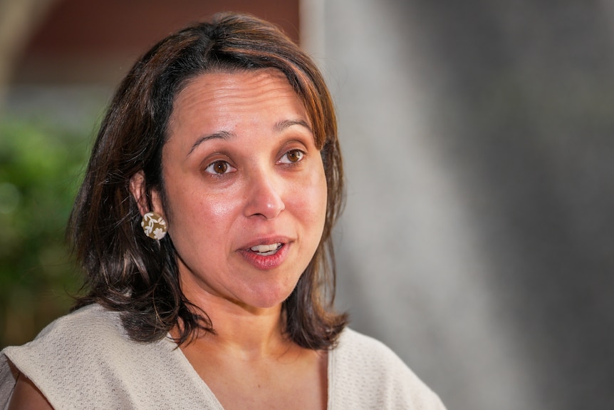 A woman with dark hair and large earrings speaking to the camera
