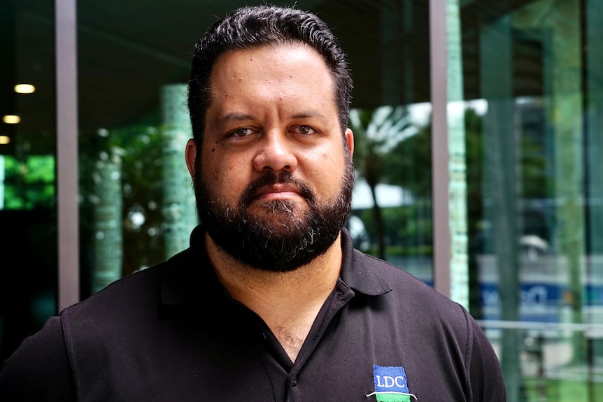 A man with a beard and wearing a black polo shirt