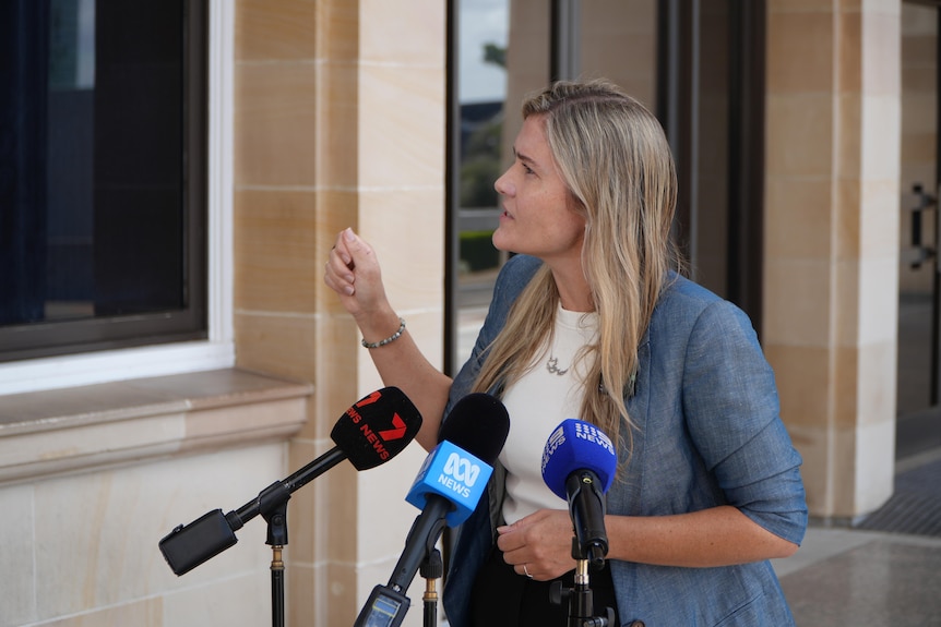 Sophie McNeill looks to her right while gesturing with her right hand. 