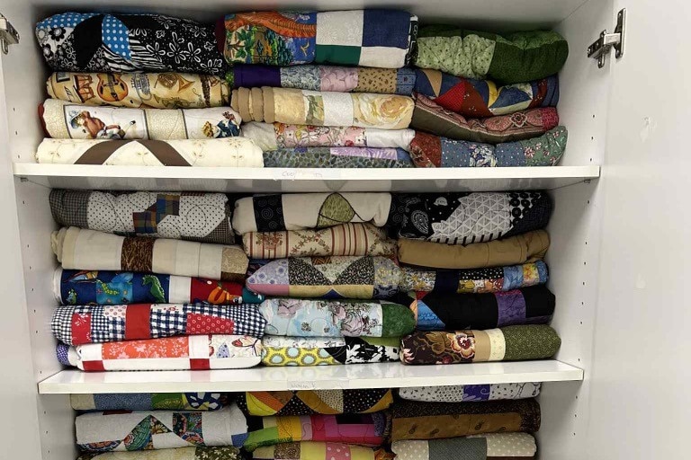 Folded patchwork quilts in a cupboard.