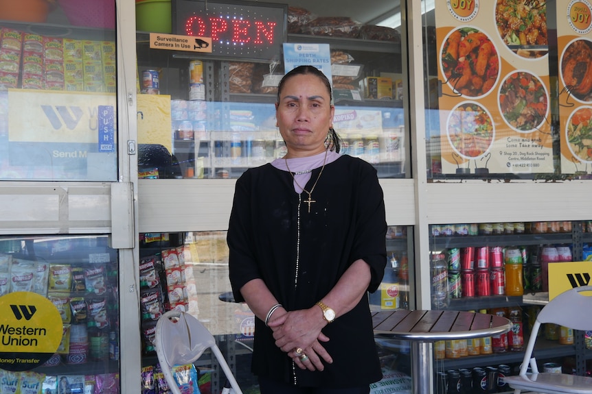 A woman standing in front of a glass and windows with adverts in them