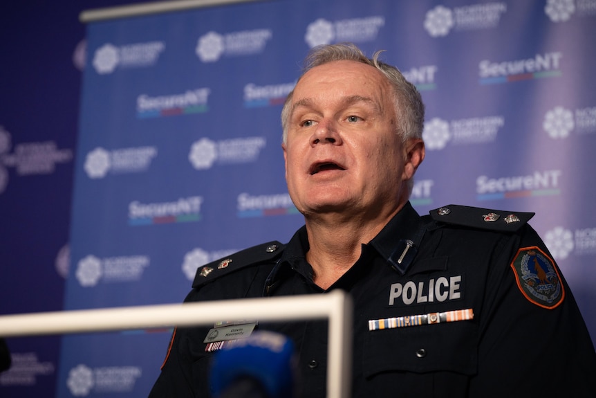 A man with short hair and blue eyes, wearing a police uniform as he speaks to the media.