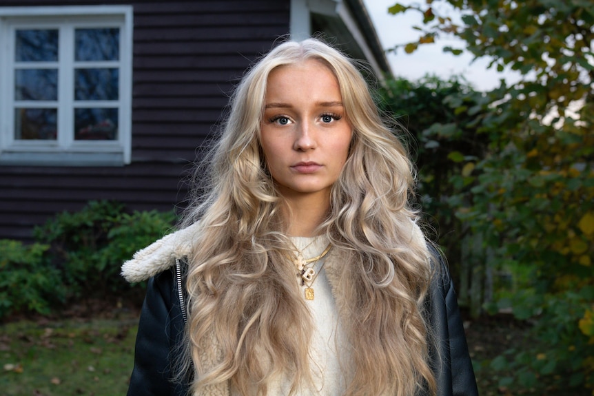 A young woman in front of a house.