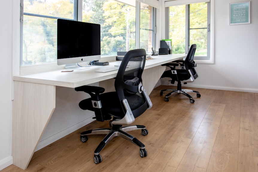 A double home office with a timber benchtop and two ergonomic chairs