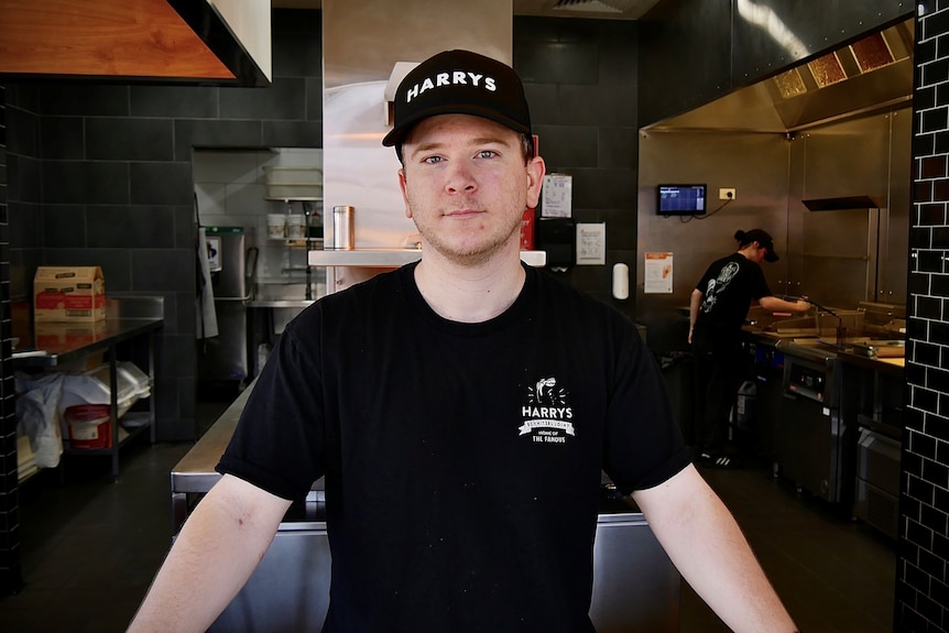 A man wearing a black cap and black shirt standing behind the counter.