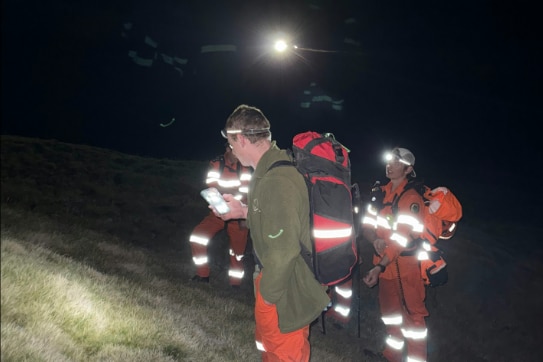 Rescue workers in high visibility clothing, at night.