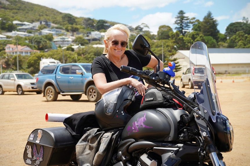 Cathy stands behind her motorbike.