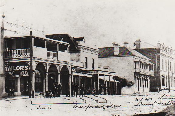 A black and white photo of shops and a street.