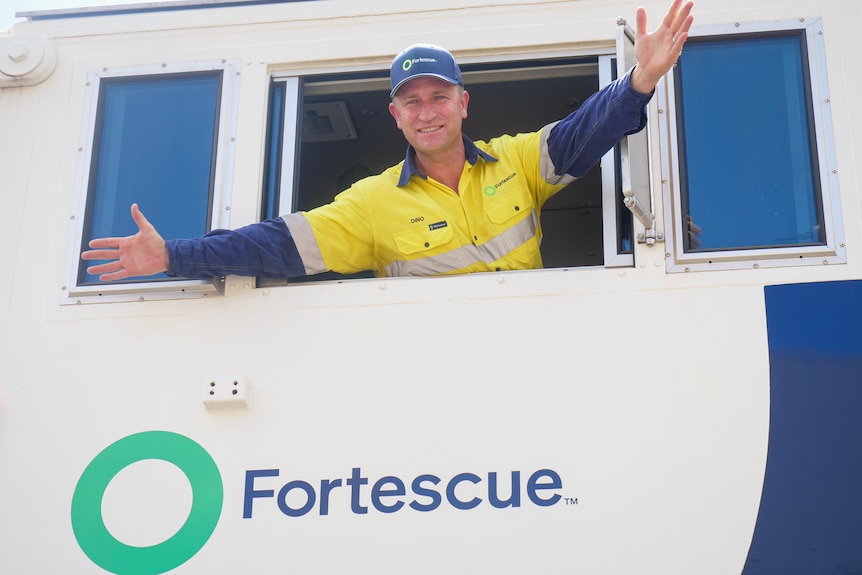 Fortescue CEO Dino Otranto holds his arms out wide from the window of the locomotive's cab.