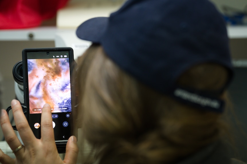 A woman reaching for an electronic device.