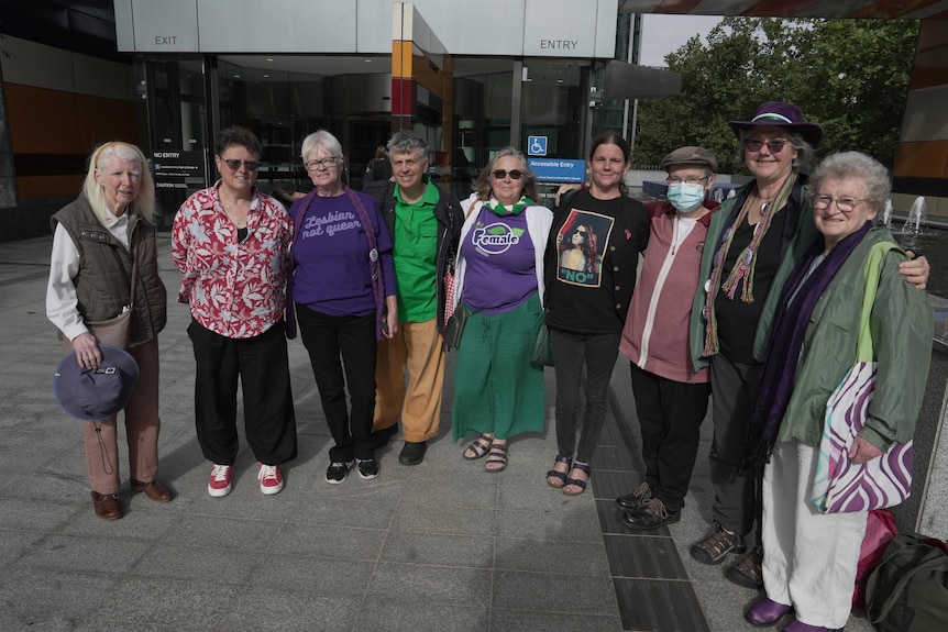 A line of women, mostly middle-aged and older, standing outside a court building.