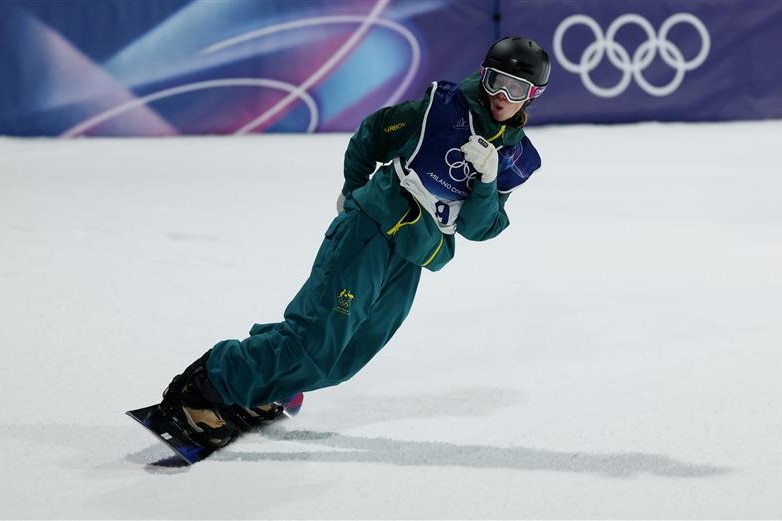 A snowboarder in green gear and helmet slides on the snow