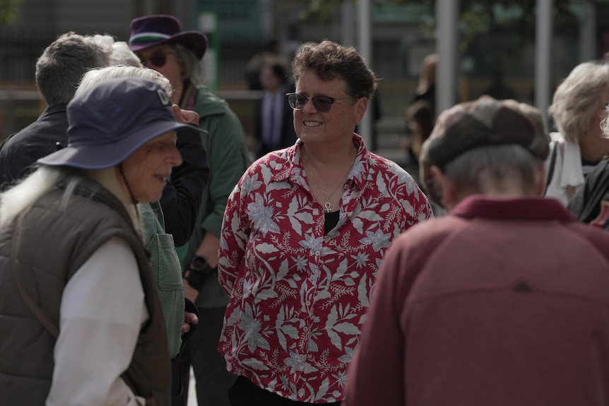 A group of middle-aged and older women standing outside a court building.