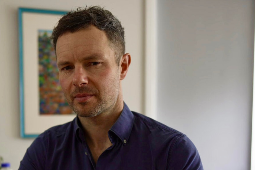 A man sitting at a table with several ultra-processed foods next to him.