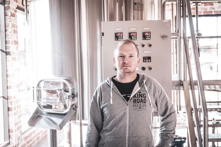 Man standing looking directly at camera in grey shirt infront of machine