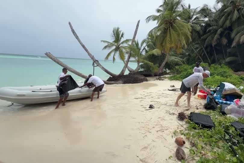 Four men pull a small boat ashore on an atoll in the Chagos Islands.