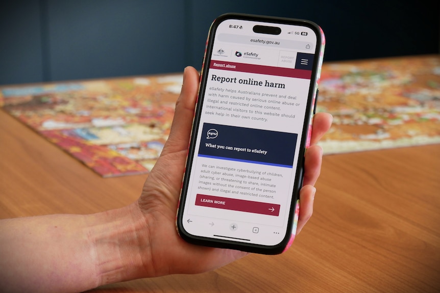 a hand holds an i-phone with the e-safety website on it