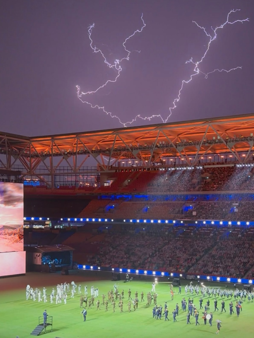 LIghtning over stadium as bagpipe band plays.