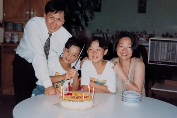 A family of four celebrating a birthday inside a restaurant.