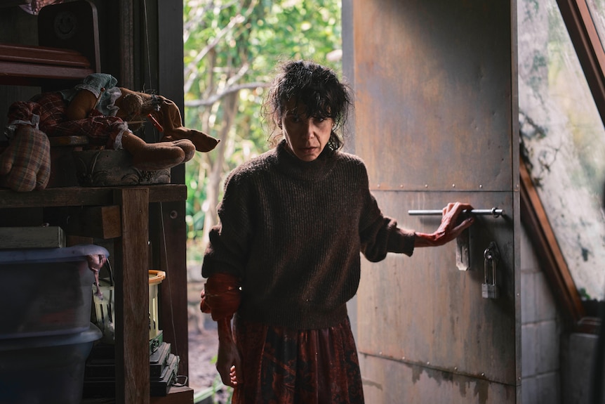 A woman looks inside an old garden shed.