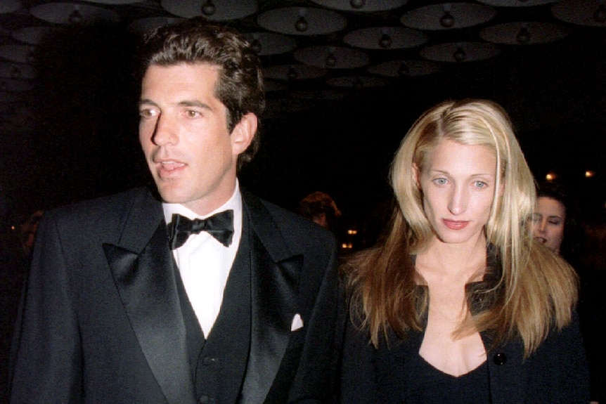 A dark-haired man in a tuxedo with a blonde woman in dark evening wear.