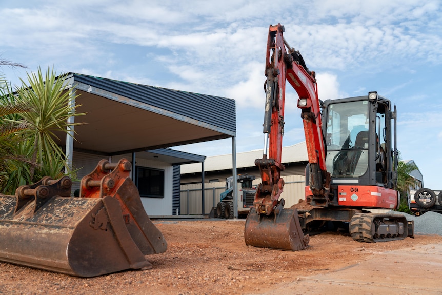 A small bobcat in front of a construction site of a modular house.