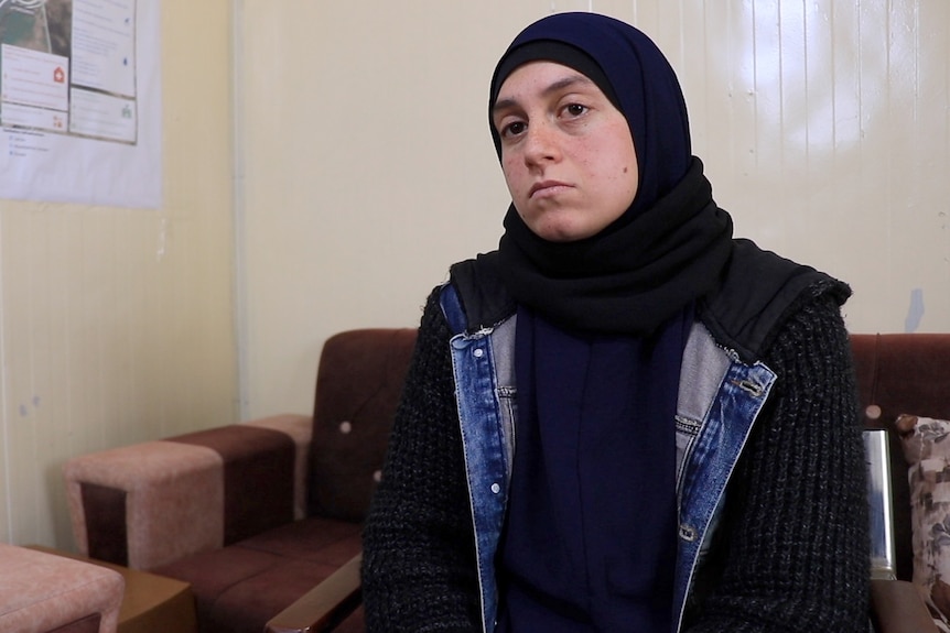 Kirsty Rosse-Emile sits in a chair wearing a head scarf during an interview in a room with a map pinned to the wall.