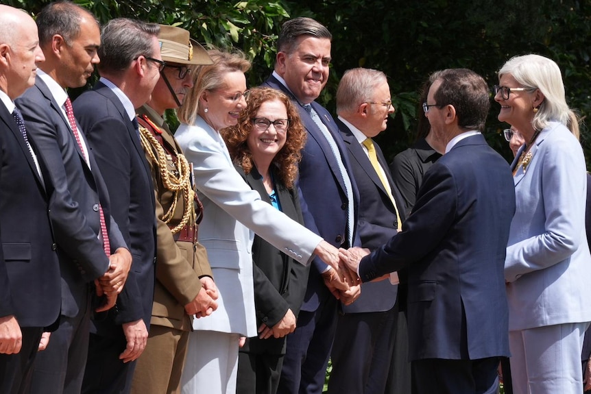 Isaac Herzog shakes hands with Sussan Ley, who is standing in a row of people.