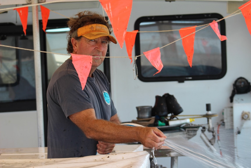 Phil de Grauw cleans his boat with a hose.