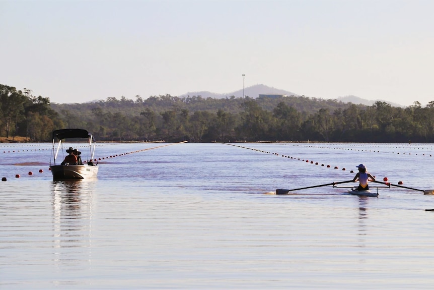 A rowing crew being followed by a boat on a rowing course.