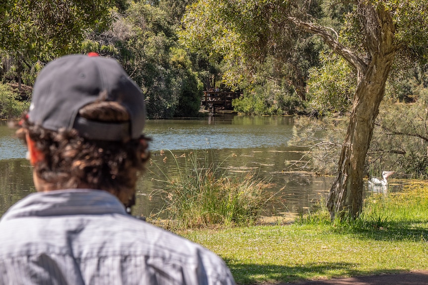 Man in baseball cap and blue shirt with long lens camera.