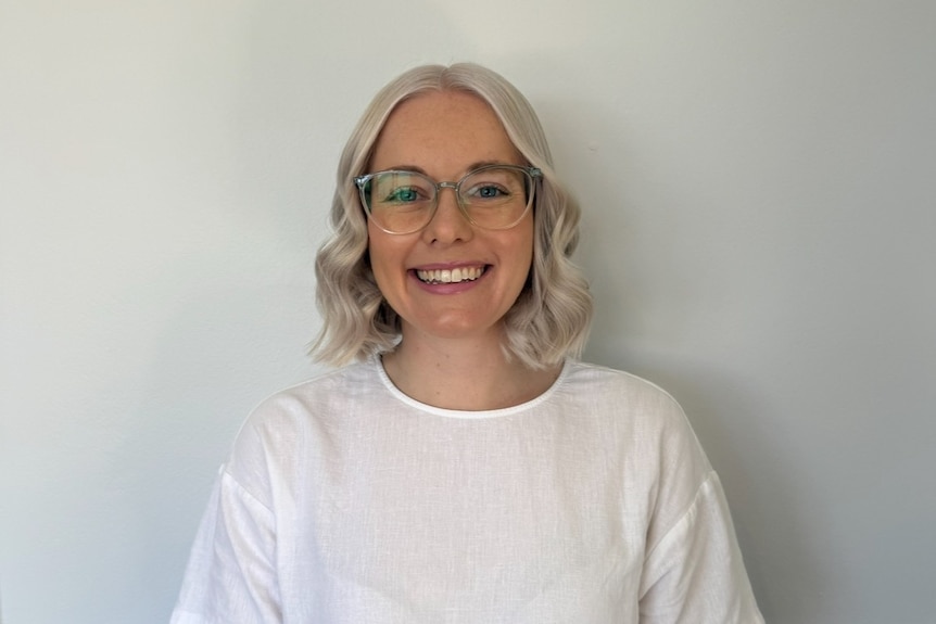 A woman with a white backdrop smiles directly to camera.
