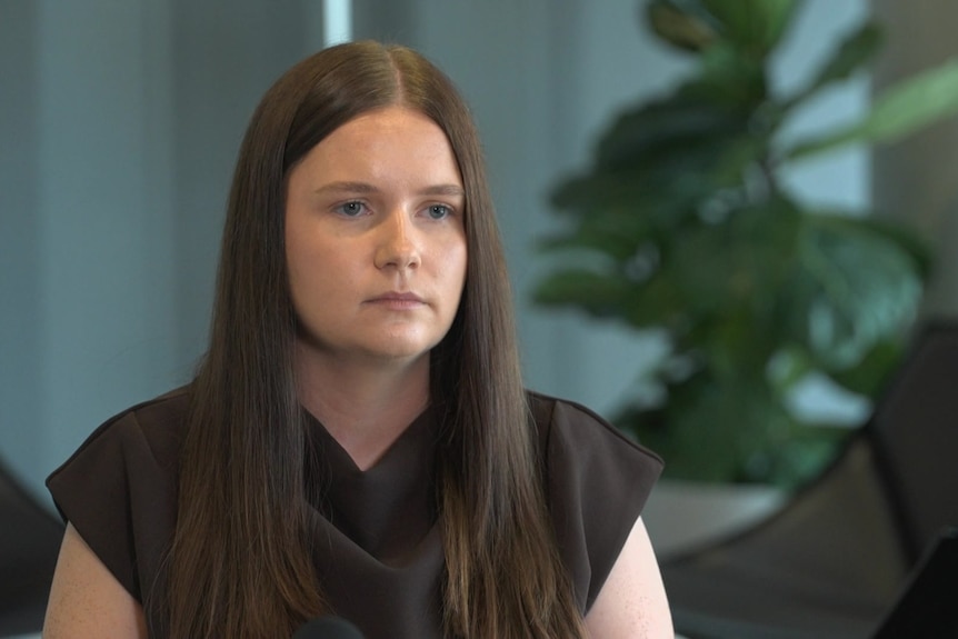 A woman with brown hair and black top looking off camera