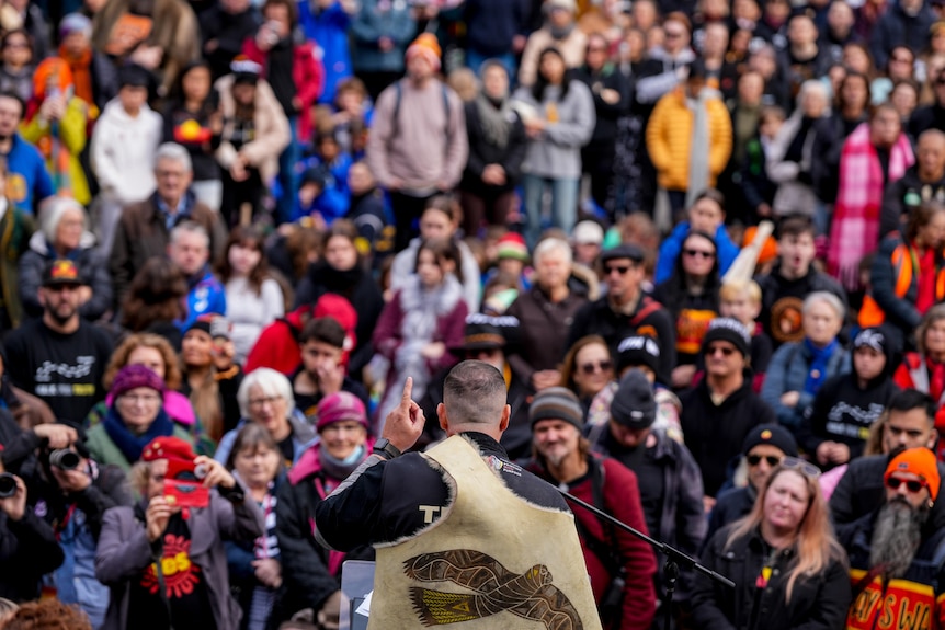 A man wearing a fur skin addressing a crowd of thousands.