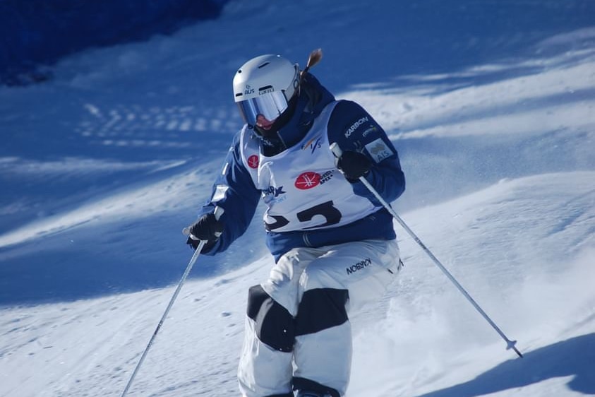 A female moguls skiier is in action skiing downhill