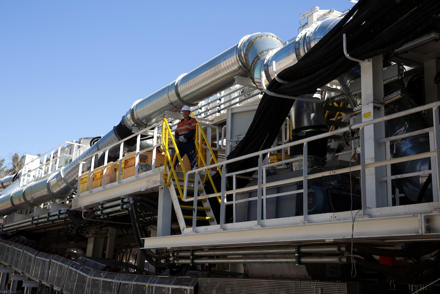 A man standing by a large machine. 