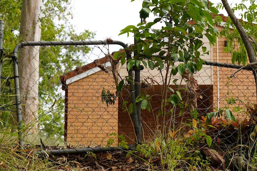 A brick home seen through a short chain link fence