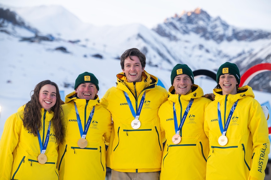 Jakara Anthony, Josie Baff, Cooper Woods, Matt Graham and Scotty James stand in front of the Olympic rings.